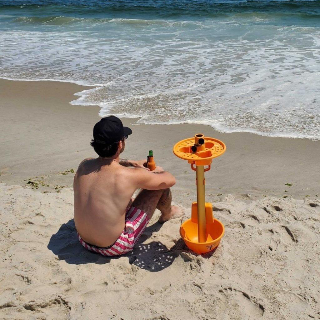man on the beach using the Anchor by Anchor Works as a table
